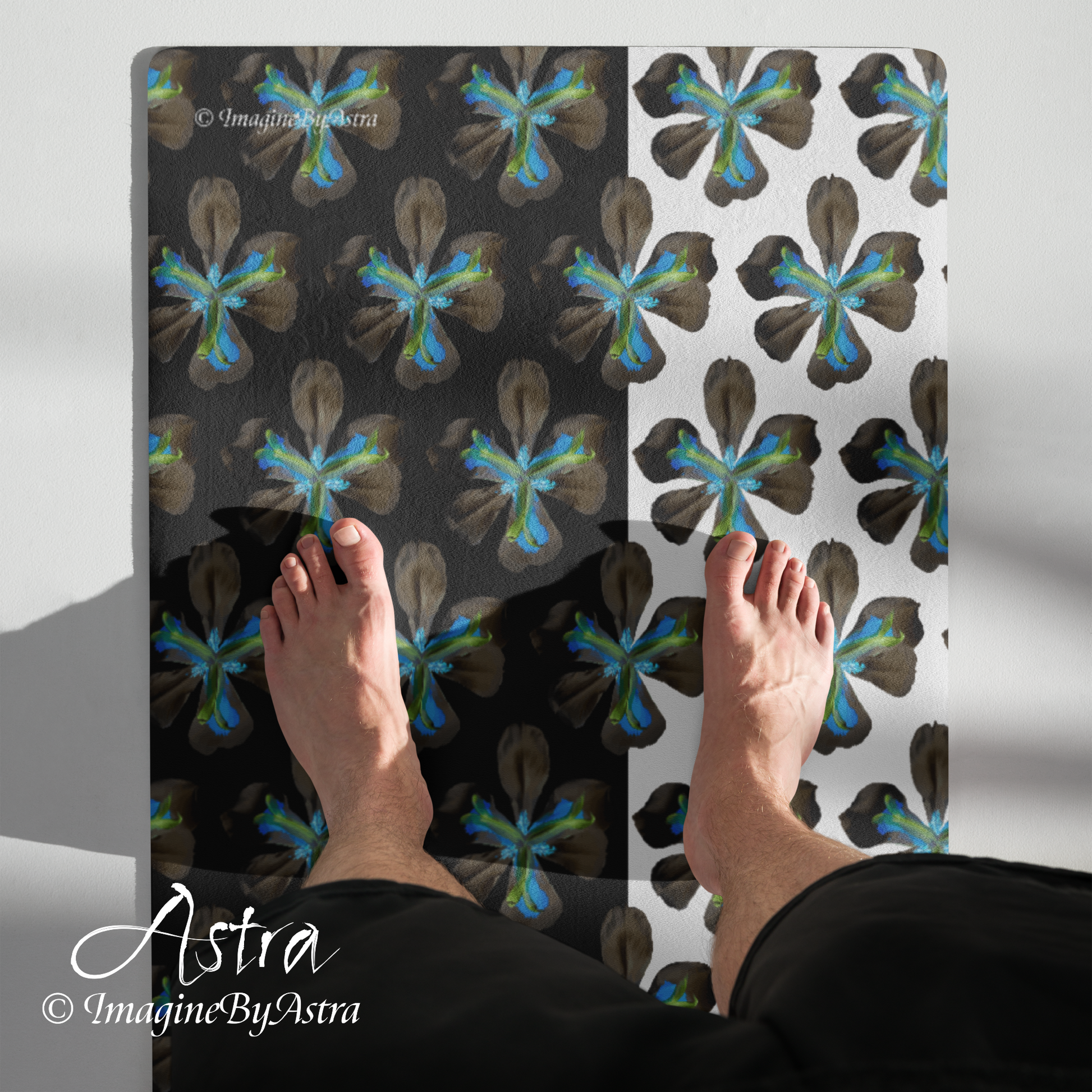 Feet are seen atop a yoga mat with a dramatic two toned black and white surface with a bright blue tropical flower print on top from the Tropical Iris Collection by Imagine by Astra Activewear.