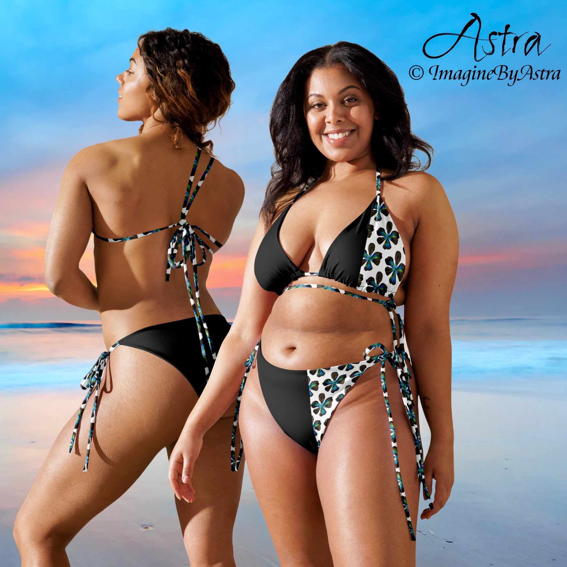 Two black women wear black and white string bikinis with a white panel running down the side with a striking tropical flower print, a beautiful beach sunset is displayed in the background. Part of the Tropical Iris Collection by designer, Imagine By Astra. From the Astra Swimwear lineup.