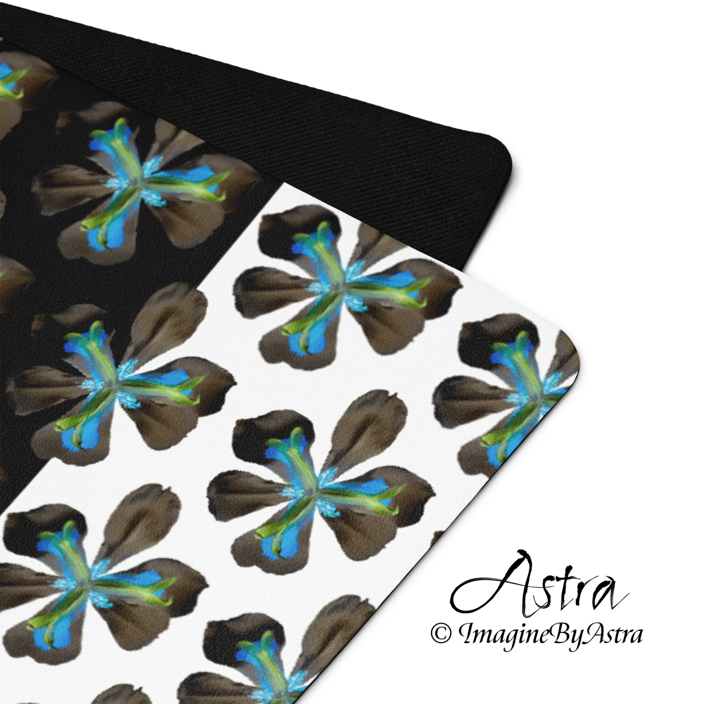 A corner of the front and back of a yoga mat is shown. The top bears a dramatic two-toned black and white surface with a bright blue tropical flower print on top. The back shows the black non slip rubber surface. From brand, Imagine by Astra Activewear.