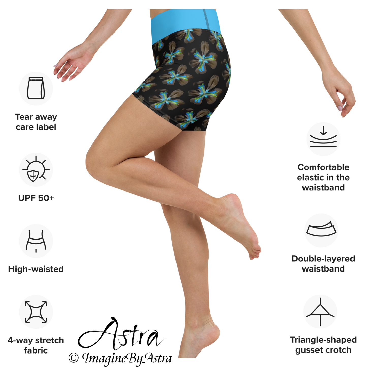 Side view of a white woman wearing a pair of black high-waisted tight fitting gym shorts with a brilliant blue floral print with matching blue waistband from the Tropical Iris Collection from activewear brand, Imagine by Astra. Her knee is drawn up, demonstrating the flexibility of the four-way-stretch fabric and comfort of the supportive double-layered elastic waistband.