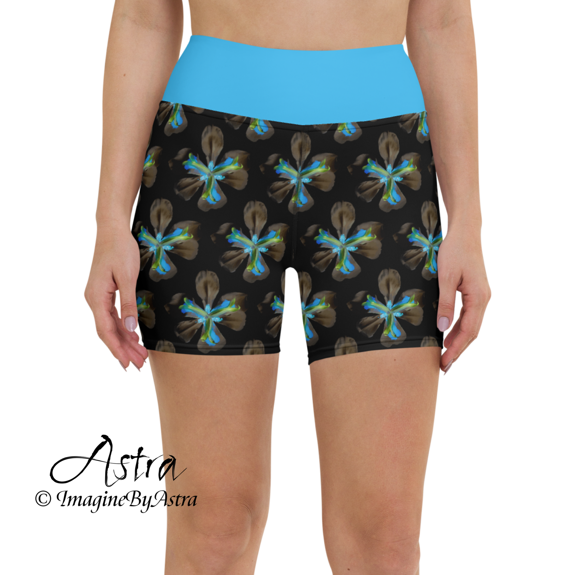 Close up front view of a white woman wearing a pair of black high-waisted yoga leggings shorts with a bright blue floral print with matching blue waistband, from the Tropical Iris Collection from activewear brand, ImagineByAstra.