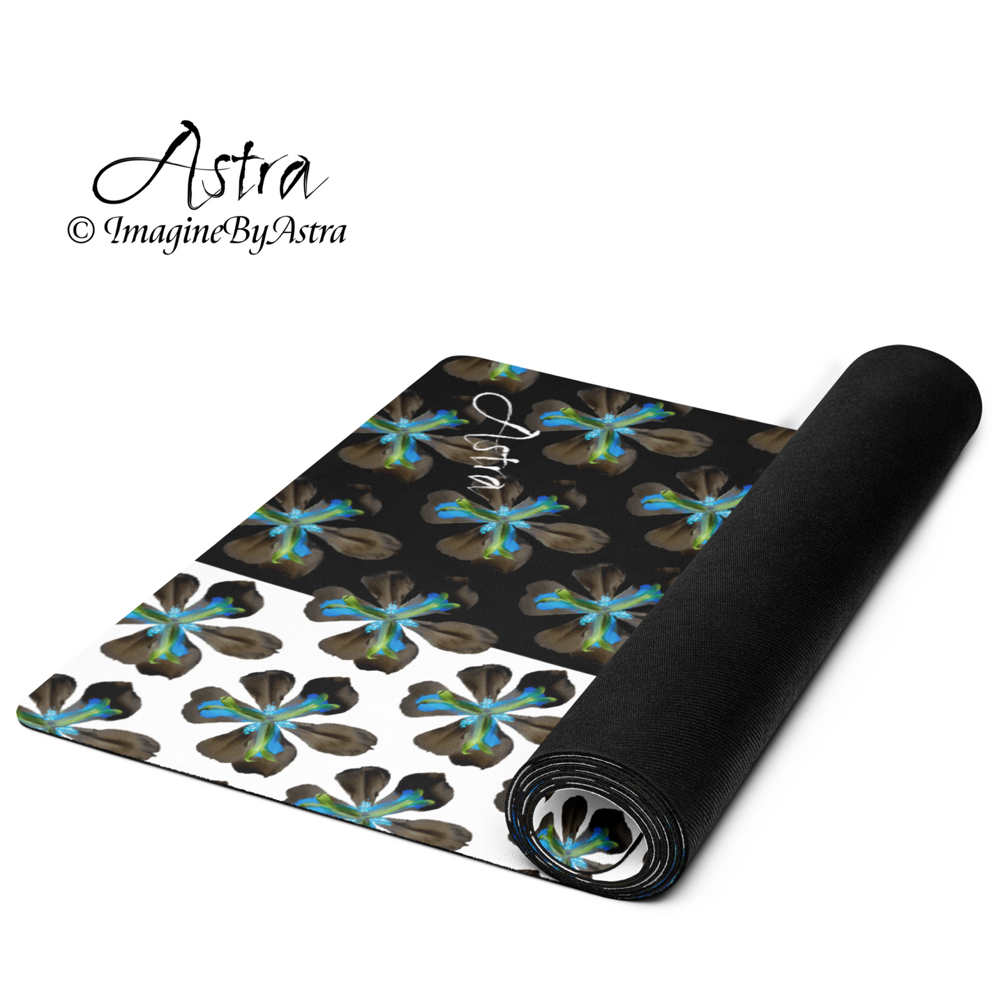 A yoga mat is partially unrolled revealing a dramatic two toned black and white surface with a bright blue tropical flower print on top, the black non slip rubber back is shown on the back of the mat. From brand, Imagine by Astra Activewear.