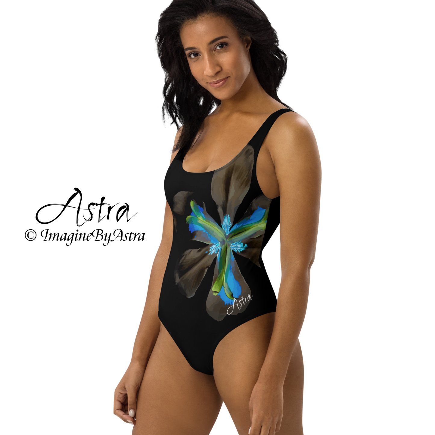 From the Astra Swimwear lineup: a black woman poses from the side, wearing a black one-piece swimsuit with a large vibrant blue tropical flower graphic down the side. The swimsuit has a flattering high cut at the hips. Part of the Tropical Iris Collection by designer, Imagine By Astra.