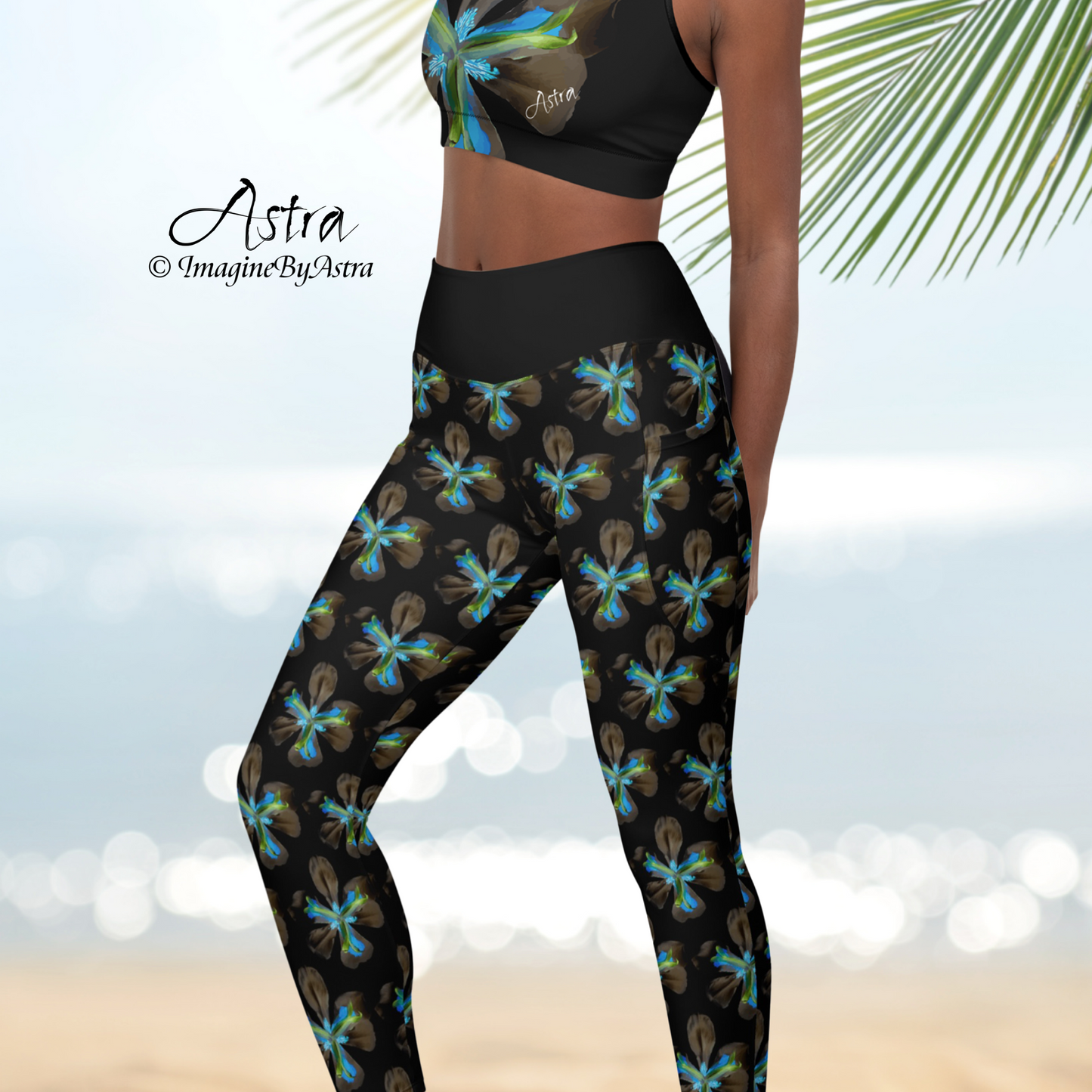 Close up on a woman with deep brown skin wearing high waisted black yoga leggings with a striking electric blue iris floral print and matching sports bra by designer Imagine by Astra.