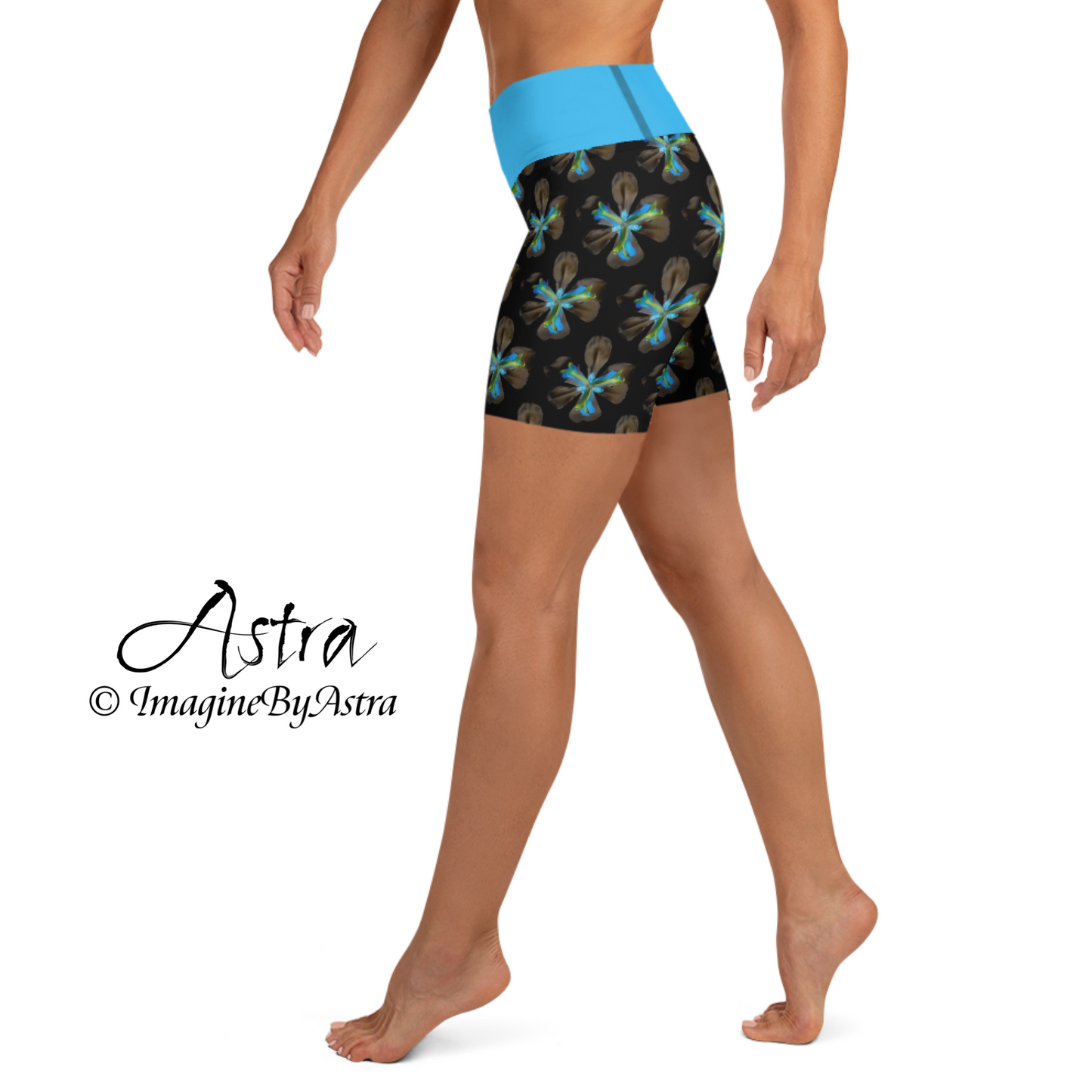 Side view of a white woman wearing a pair of black high-waisted yoga shorts with a brilliant blue tropical flower print and matching blue waistband from the tropical iris collection from designer, ImagineByAstra.